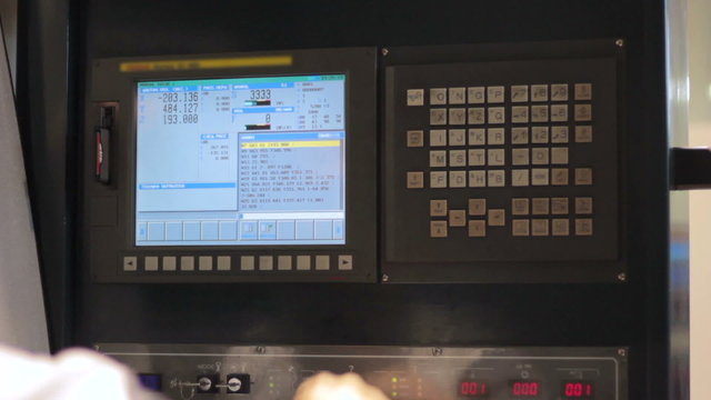 Operator working with control panel of CNC machining centerchanging numbers