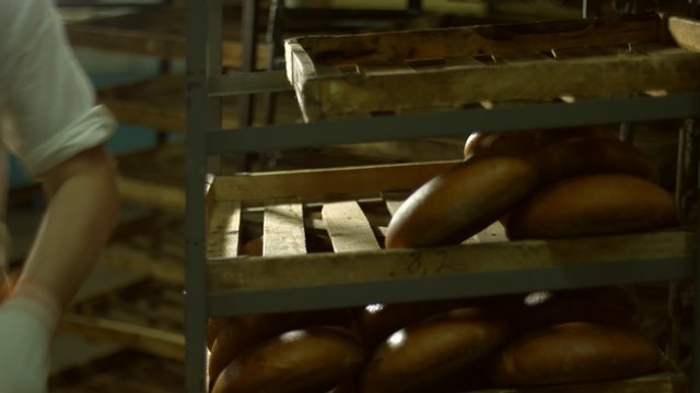 Baker puts freshly baked bread on the shelves.