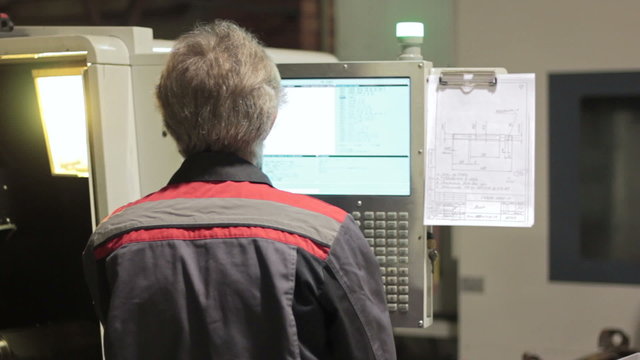 Operator working with control panel of CNC machining centerchanging numbers