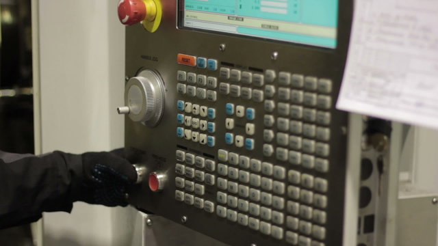 Operator working with control panel of CNC machining centerchanging numbers