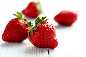 Ripe red strawberry on a blue wooden table