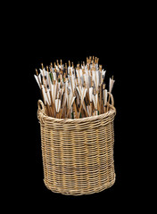 Large number of archery arrows in a wicker basket, isolated on black.