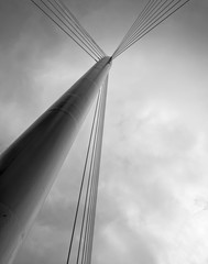 Pylon with cables, part of the structure of an urban bridge, against a dark, threatening sky.