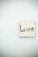 Black love text on handmade white jewellery closeup, background