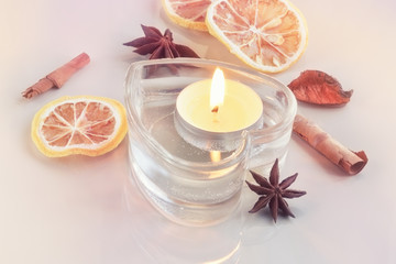 Burning candle in a heart with spices and bokeh in the backgroun