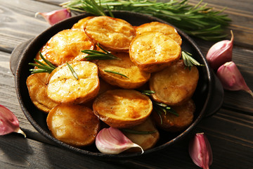 Delicious baked potato with rosemary in frying pan on table close up