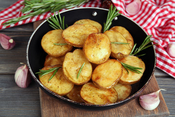Delicious baked potato with rosemary in frying pan on table close up