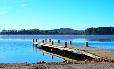 Wooden dock pier extending over blue lake water.