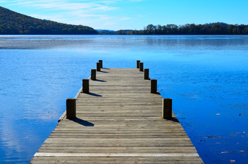 Wooden dock pier extending over blue lake water.