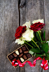 roses and chcolate on wooden surface