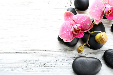 Beautiful composition of orchid and pebbles on white wooden background, copy space
