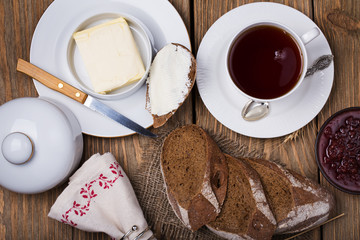 Homemade bread with butter, black tea and raspberry jam