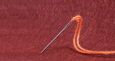 Тeedle anb Thread of  Yarn on the Red Felt Fabric Background Te