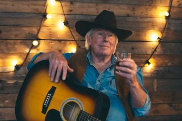 Country and western musician sitting with guitar. Having a drink