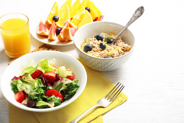 Tasty oatmeal and vegetable salad on wooden background. Healthy eating concept.