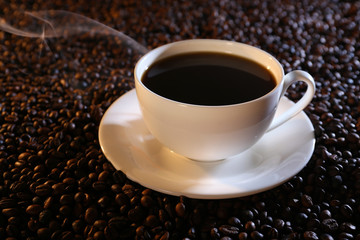 Obraz na płótnie Canvas Cup of hot coffee on coffee beans background
