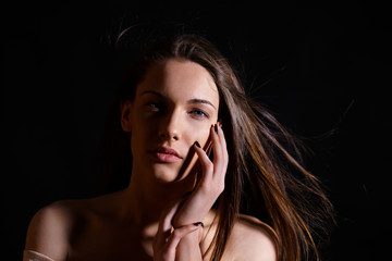 Portrait of beautiful brunette woman with natural look and without makeup on black background