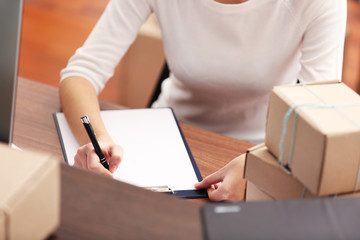 Delivery concept. Woman signs papers among parcels, close up