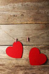 Red felt hearts hang on cord against wooden background