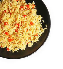 Stewed rice with a carrot on a black plate over white background