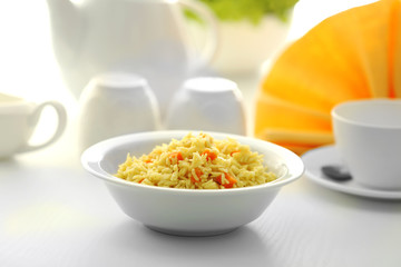 Stewed rice with a carrot in a white bowl on a table
