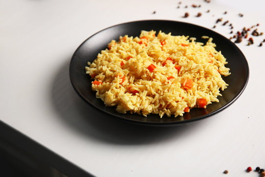 Stewed rice with a carrot on a black plate
