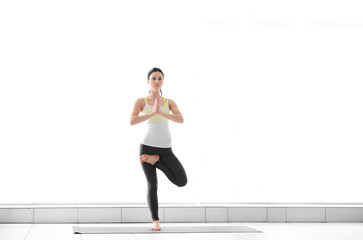 Fototapeta premium Young woman practicing yoga tree pose for balance and mindfulness, fitness and wellness lifestyle, this fitness activity promotes overall wellness and a healthy lifestyle
