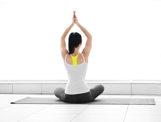 Health concept. Young attractive woman does yoga exercise in the gym  against white wall