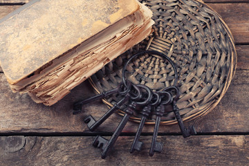 Fototapeta na wymiar Composition of old books, keys and other things on wicker plate against wooden background, close up