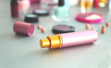 Perfume bottle with makeup cosmetics on a table, close up