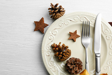Christmas serving cutlery on plate over light wooden table, close up