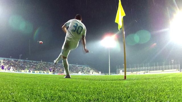 Soccer player takes a corner kick. Close-up of a soccer player kicking a football near the corner flag on a green grass pitch during a competitive match.
