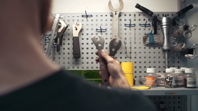 Mechanic is taking tool from tool wall