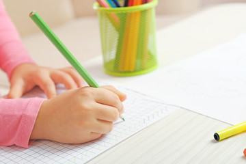 Child drawing with pencils on paper, closeup