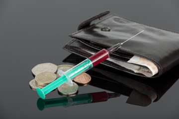 Fototapeta premium Blood filled hypodermic needle laying across some cash