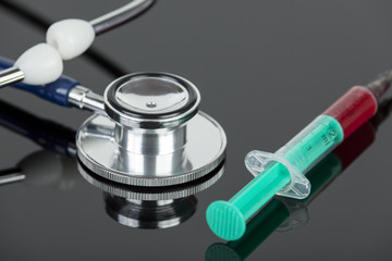 Blood filled hypodermic needle with stethoscope on lab table