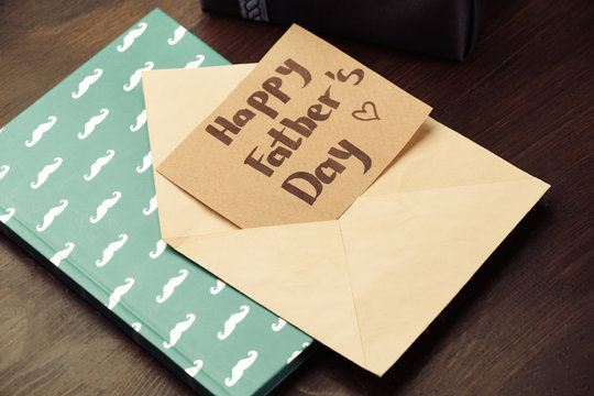 Happy Father's Day card and notebook with mustache print on wooden background