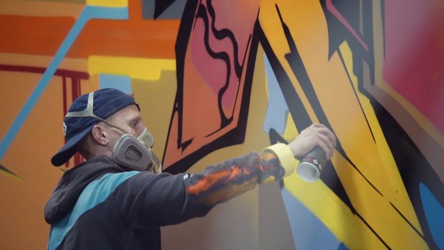 Graffiti artist painting on the wall, interior