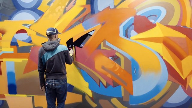 Graffiti artist painting on the wall, interior