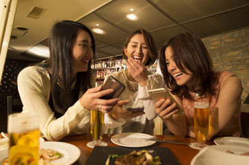 Three women are laughing while looking at the smartphone