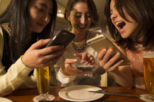 Three women are laughing while looking at the smartphone