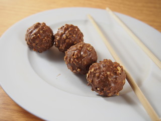 Milk chocolate balls with almond and peanuts on white dish