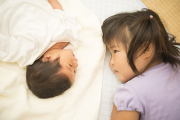 Obraz na płótnie Canvas 見つめ合う新生児の弟とお姉ちゃん