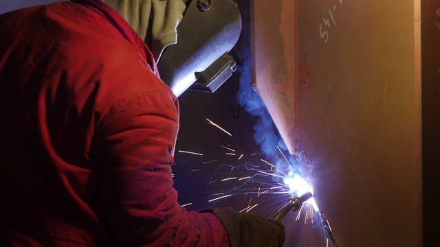 workers welding metal parts in big modern shipyard
