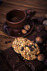 Roasted coffee beans, chocolate, muesli, candy, nuts and cup on the wooden background