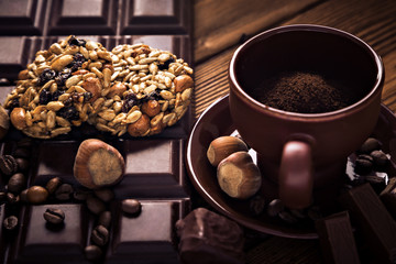 Roasted coffee beans, chocolate, muesli, candy, nuts and cup on the wooden background