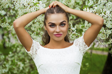 Fototapeta premium Happy young woman in white dress against the background spring f