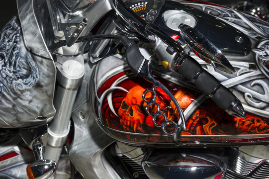 Classic chopper motorcycle with brake lever in the shape of brass knuckles and bodywork with aerography, fire sculls and celtic pattern 