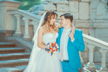 Naklejka premium Newlyweds standing on stairs, looking at each other and smiling
