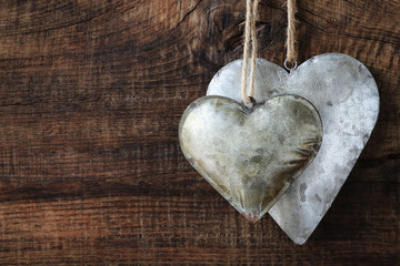 Shabby tin hearts on rustic wooden background. With copy space